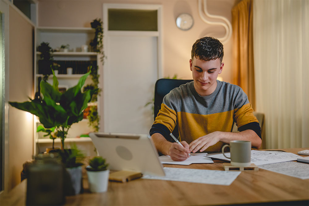 Young man teenager student study at home at the table night