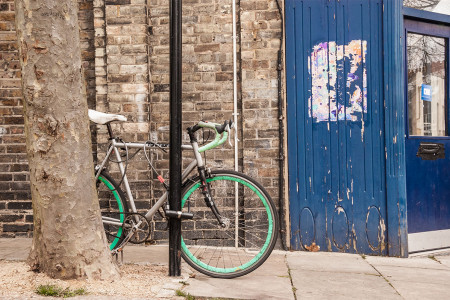 Cool single gear road bycicle locked to a street lamp